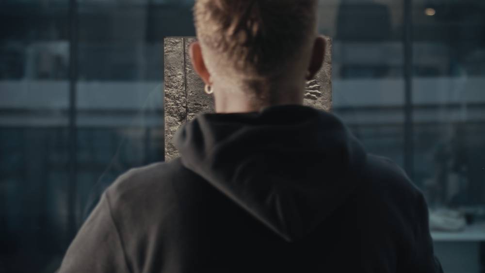 Still from the film SaF05 by Charlie Prodger: a person seen from behind standing in front of an artwork