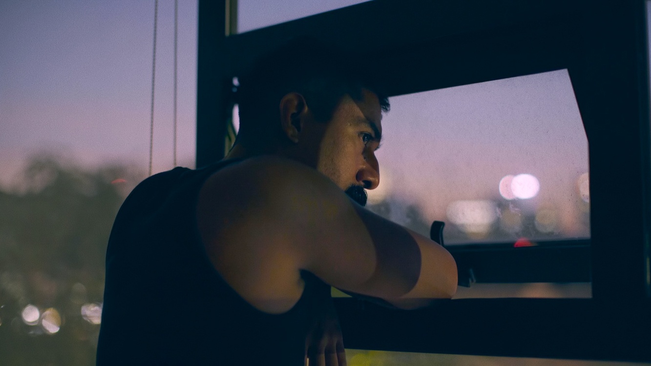 Still from the film Pornomelancholia by Manuel Abramovich: Lalo Santos is looking out from the window in the evening